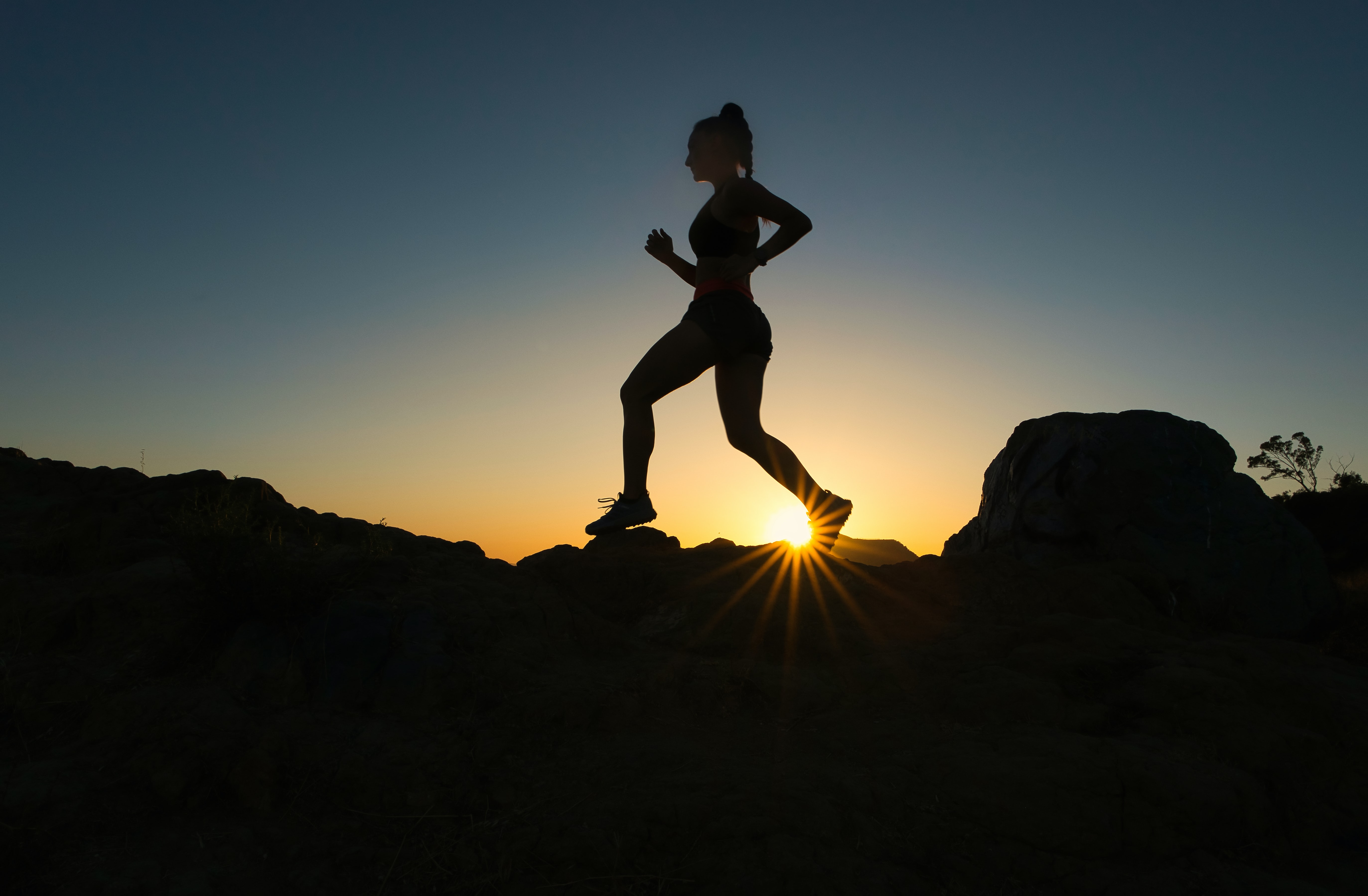 Woman runs up a trail during sunset